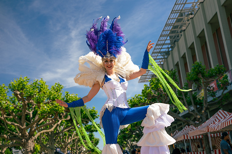 A performer on stilts from the Daring Arts Movement performs in front of the MLK Student Union.