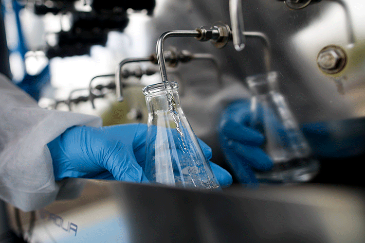 A photo shows a gloved hand filling a flask with water from a tap