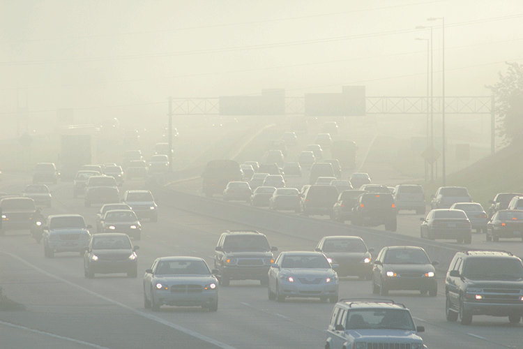 A photos shows a busy highway that is obscured by smog