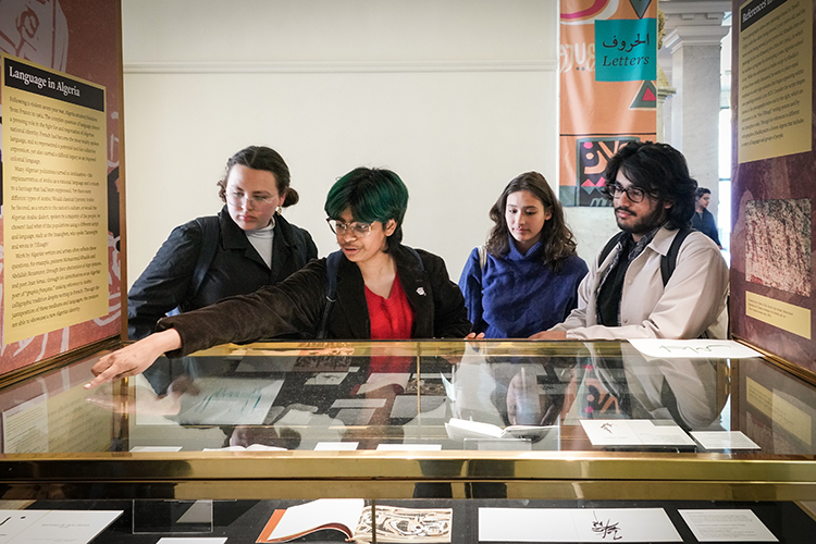 four students look at items in a glass case