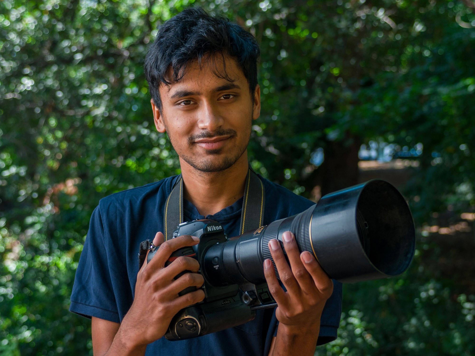 A portrait of Vishal Subramanyan holding a large camera.