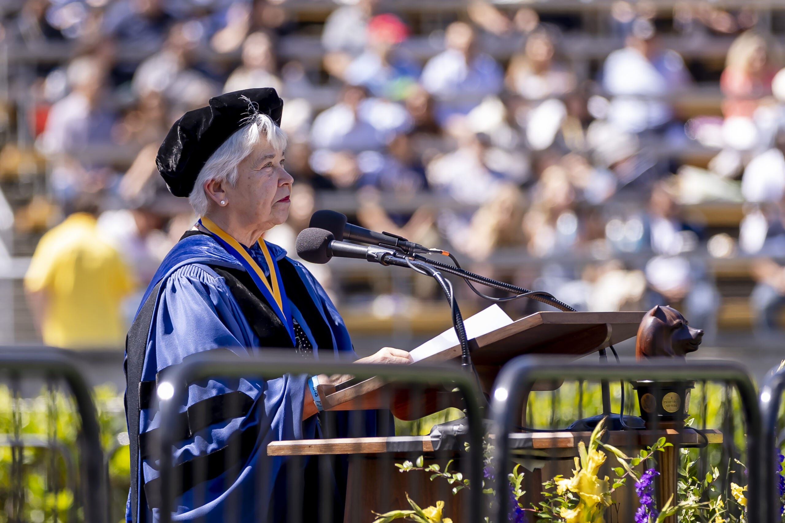 Chancellor Carol Christ stands at a podium wearing academic regalia.
