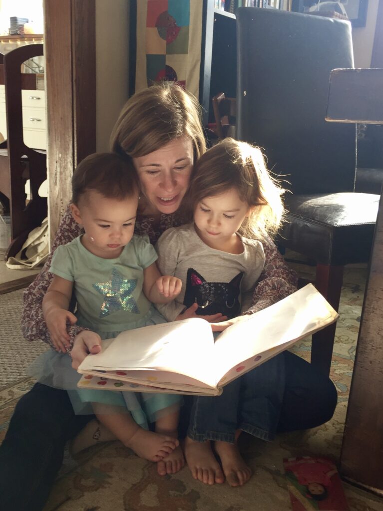 Julie Lucas with her nieces, seated on the floor reading a book