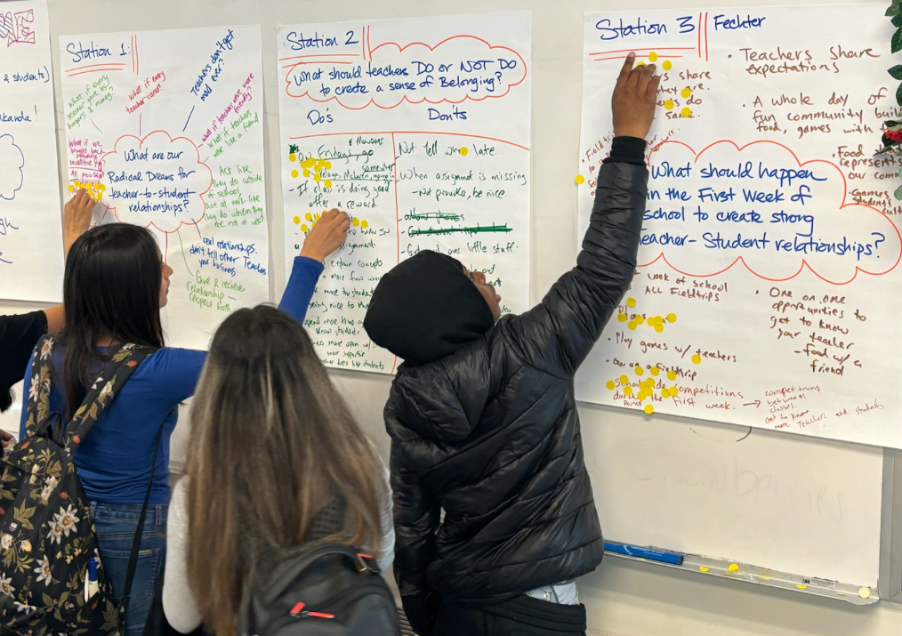 Students point toward poster paper on the wall during an exercise about the ways to better understand chronic absenteeism among students.