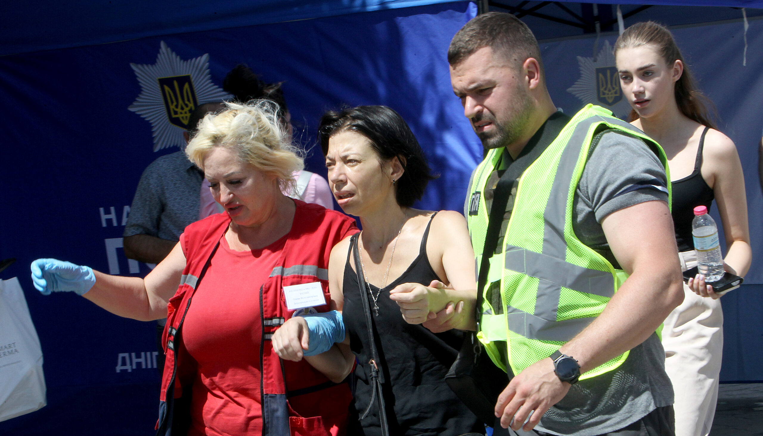 Rescue workers lead a disoriented and possibly injured woman from a Ukrainian shopping center targeted by Russian missiles.