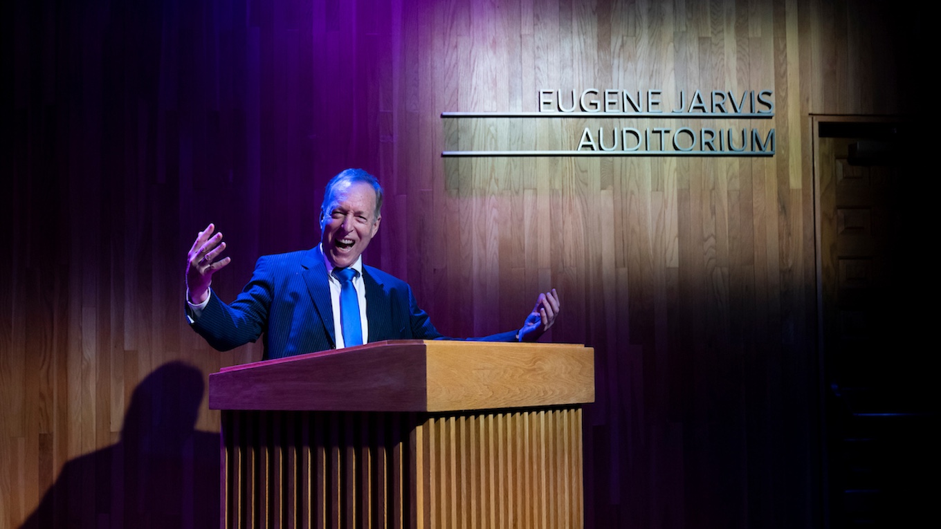 Eugene Jarvis stands at a podium giving a speech in the Eugene Jarvis Auditorium.