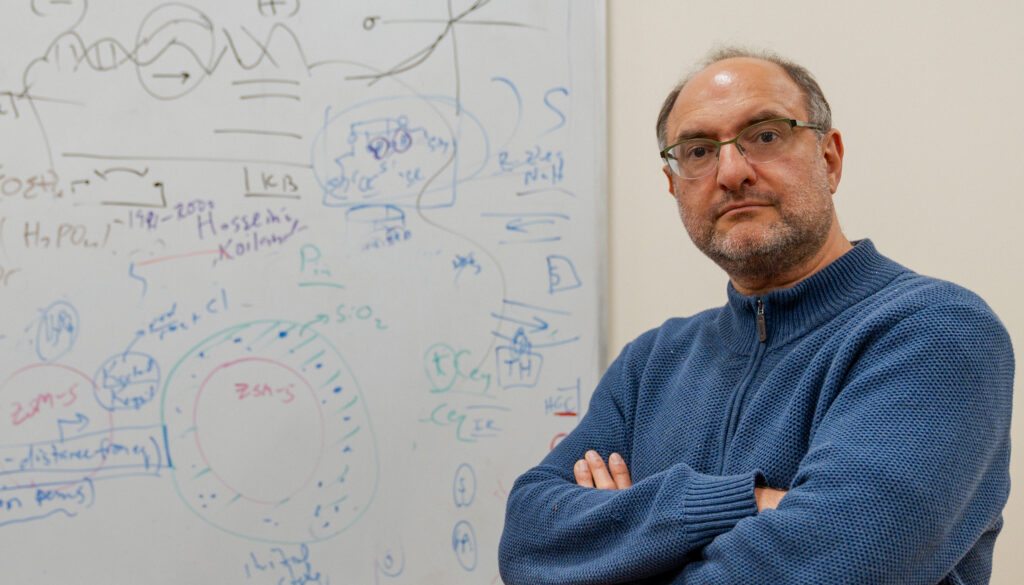 man with arms crossed standing in front of a white board with equations